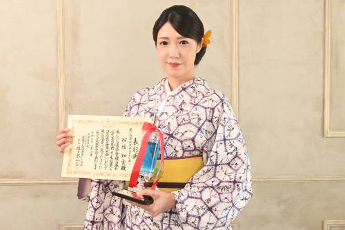 表彰状とトロフィーを手に笑顔の松橋知実さん