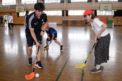 田中健太郎選手(左)らフリーブレイズの選手とフロアボールを楽しむ児童