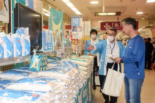 買い物客(右)に「はれわたり」をPRする青森県職員=14日、青森市