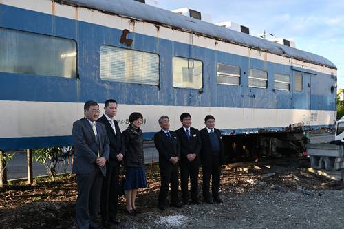 安全祈願祭の後、「サシ581形食堂車」の前で記念写真に納まる関係者=23日、八戸市