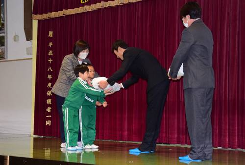 フラップあぐり北三沢の木村透副代表理事(右から2人目)から新米を受け取る園児