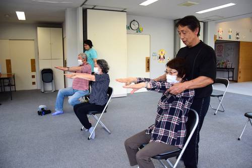 村越信市さん(右)の指導を受けながら、上半身のストレッチをする参加者