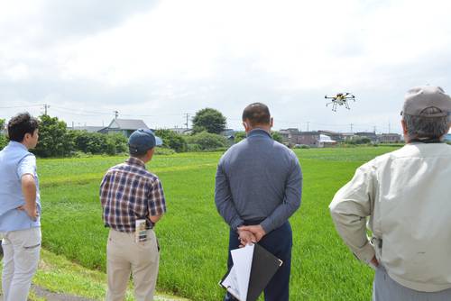 ドローンのデモフライトを見学する生産者=18日、青森市