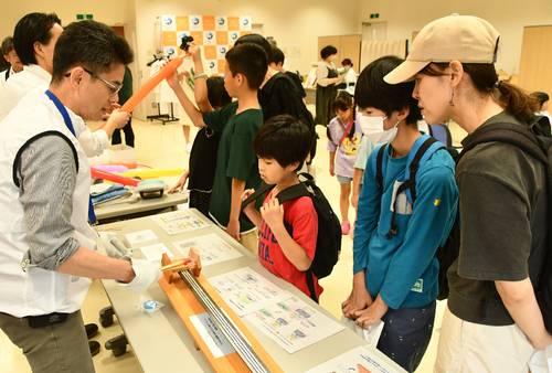 超伝導について説明を受ける見学者