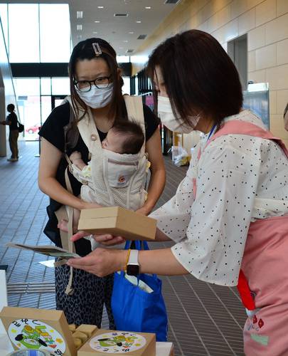 来場者(左)に積み木を配布する八戸市の担当者