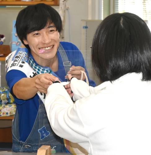 女性職員にマシュマロを配って回る神久保翔也さん(左)