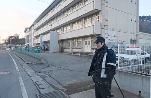 クマの目撃情報を受け、八戸市立根岸小前で警戒に当たる八戸署員(右)=31日午後4時半ごろ