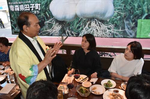 田子産ニンニクを使った料理を味わいながら山本晴美町長(左)の説明に耳を傾ける来店客