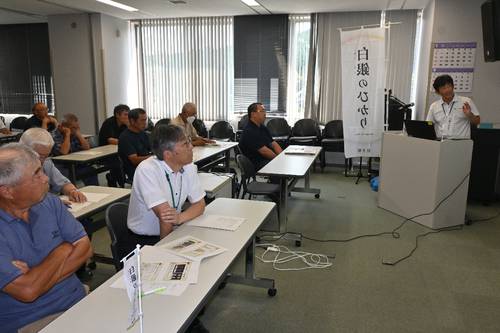 岩手県県北農業研究所の伊藤信二上席専門研究員(右)の説明を聞く出席者=16日、久慈市