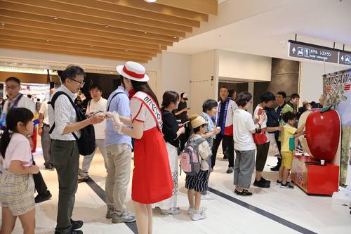 「リンゴジュースが出る蛇口」に並ぶ来場者=26日、伊丹空港(三沢空港ターミナル提供)