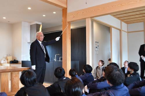 完成した住宅で学生に講話する大山重則会長(奥左)=21日、弘前市