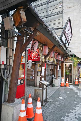 地震の影響で傾いたみろく横丁の門。柱をパイプで補強している=10日、八戸市六日町