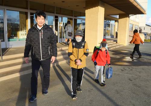迎えに来た保護者と一緒に下校する児童。臨時休校や保護者引き渡しルールの周知が課題となっている=12日午後、八戸市内