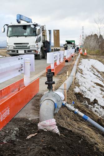 町道石沢・後平線の道路脇に敷設された仮設配水管=18日、七戸町