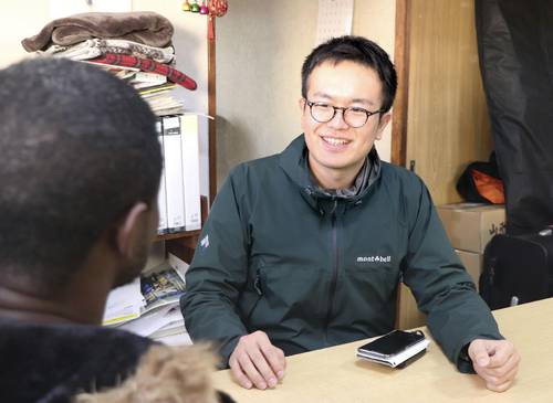 アフリカ出身の男性(手前)と話す「つくろい東京ファンド」の大沢優真事務局長=2025年12月、東京都中野区