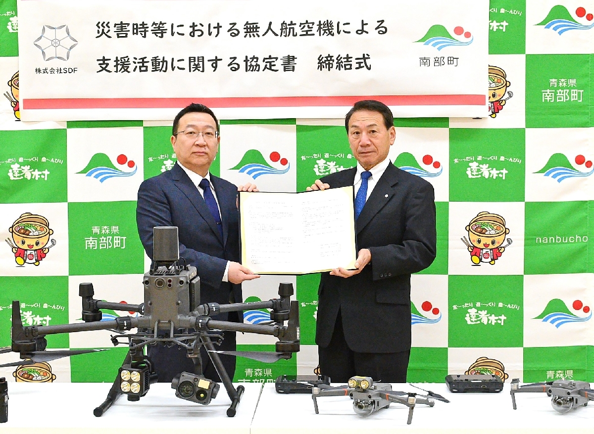 協定書を交わした梅内勝代表(左)と工藤祐直町長