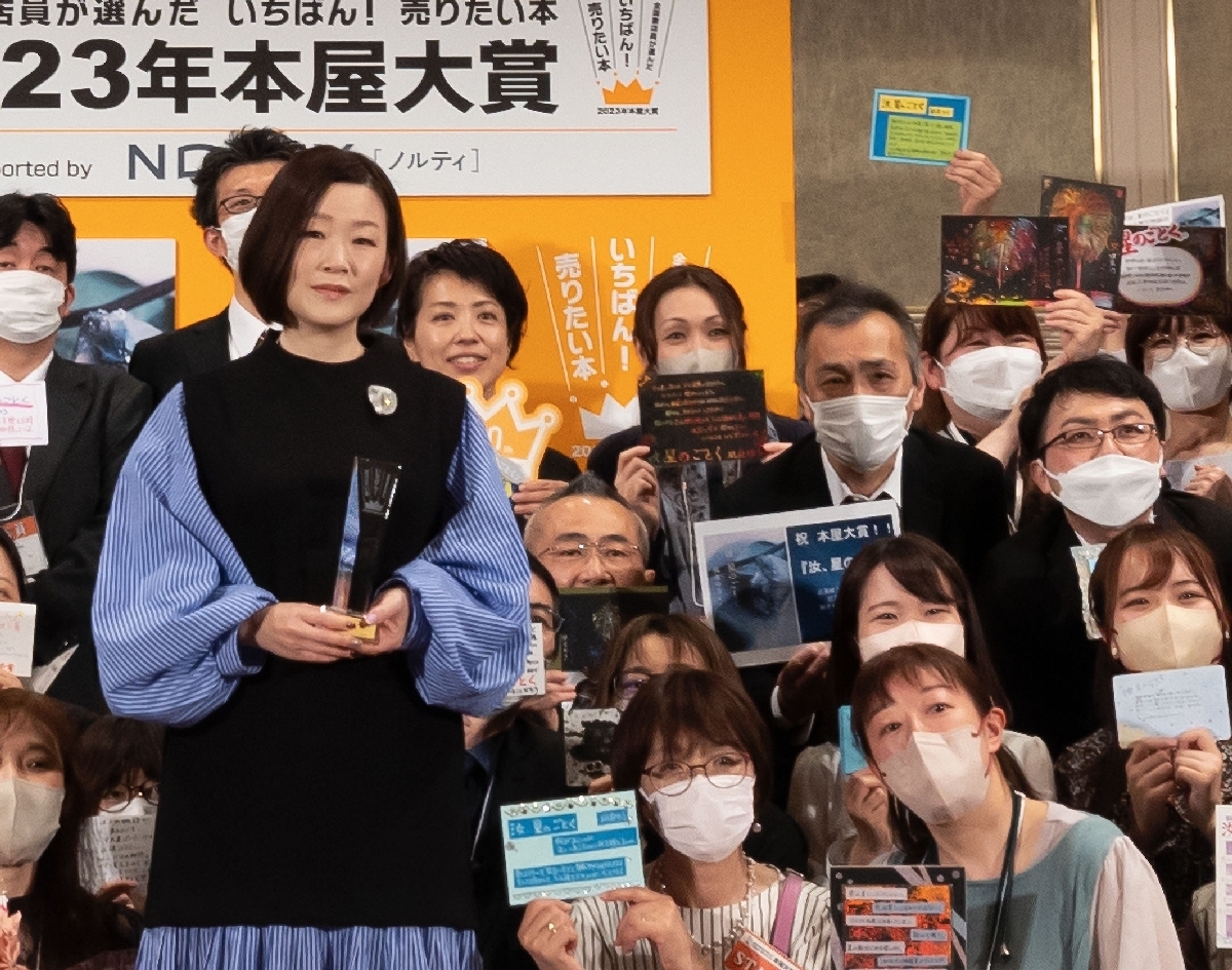 本屋大賞の発表式で、大賞となった凪良ゆうさん(左)を囲み、記念撮影をする櫻井美怜さん(前列右)ら全国の書店員=昨年4月、都内(講談社提供)