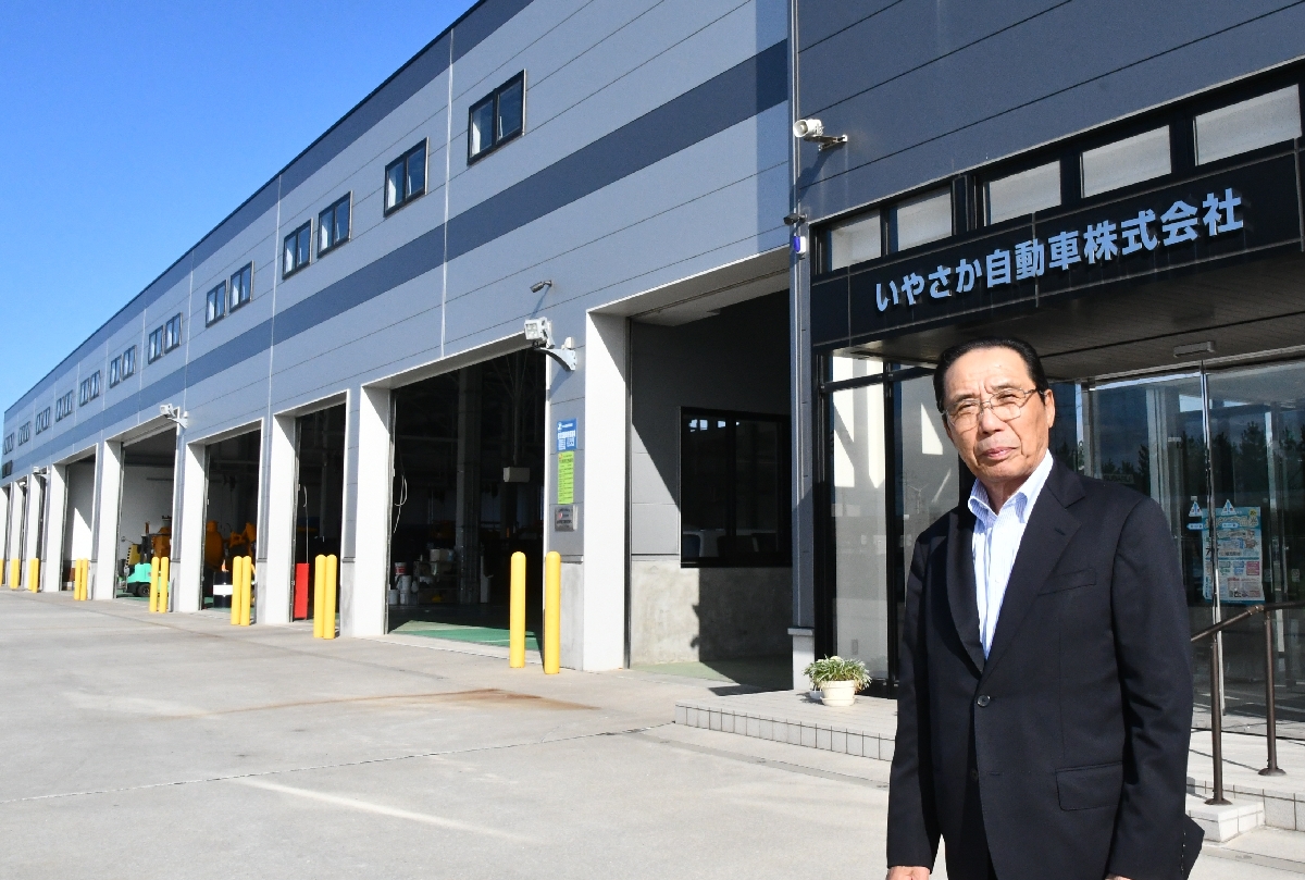 弥栄平中央地区に立地する営業所を背にする田村七郎さん=9月、六ケ所村